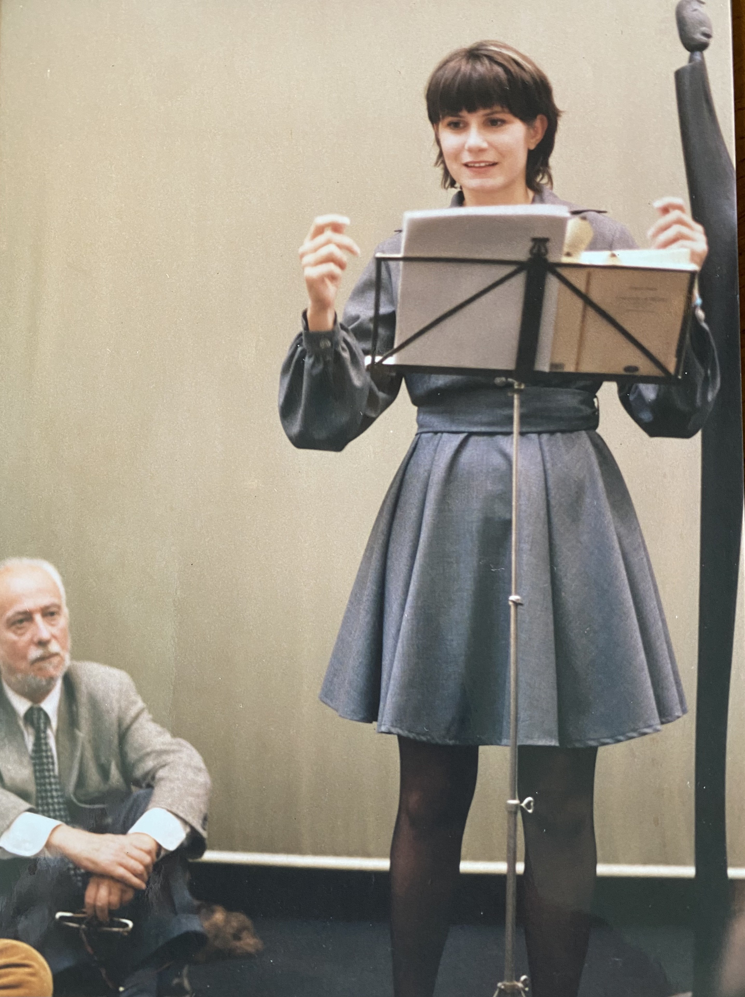 Chiara Bazzoli legge al leggio in una galleria d’arte milanese durante Non dimenticare il tuo cuscino, 1996